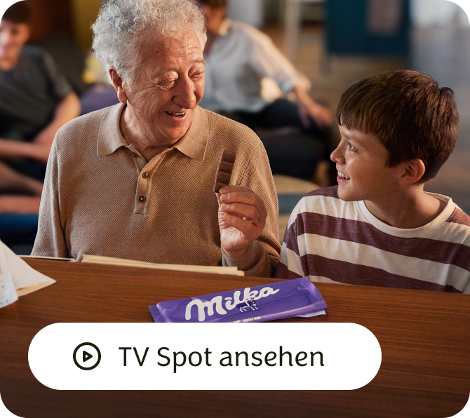 Ein Man spricht mit einem Junge der ein MILKA Produkt hat